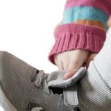 Kind schließt den Klettverschluss an Schuh